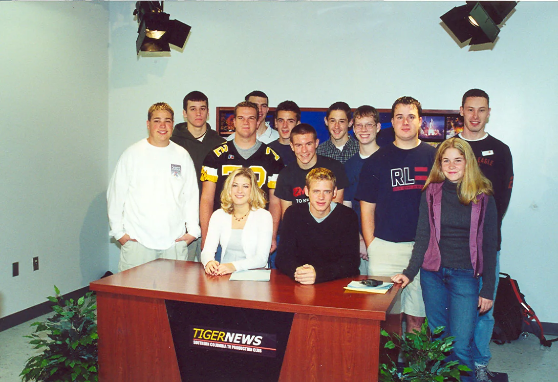 A group gathered around the wooden Tiger News studio desk.